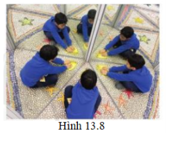 Sự tạo ảnh qua hai gương a) Khi đi tham quan nhà gương ở công viên, một bạn học sinh thấy một em bé ngồi trước hai gương phẳng ghép với nhau thì có rất nhiều ảnh trong gương (hình 13.8). Bạn học sinh đó thắc mắc, không biết số ảnh trong gương phụ thuộc vào yếu tố nào? Em hãy đưa ra câu trả lời dự đoán.